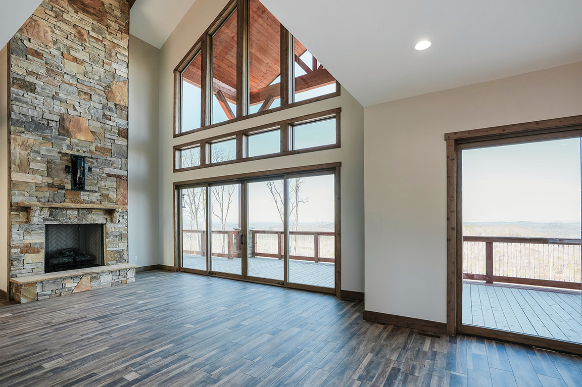 Living room with stone fireplace and large windows overlooking deck.