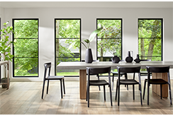 four fiberglass windows behind a contemporary kitchen table with black chairs.