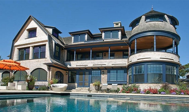 expansive Rhode Island home with custom blue windows and patio doors as seen from the luxurious backyard
