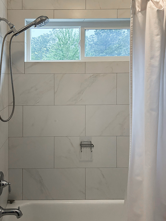 Marble tiled shower with a high window in a Houston Woodland Home.