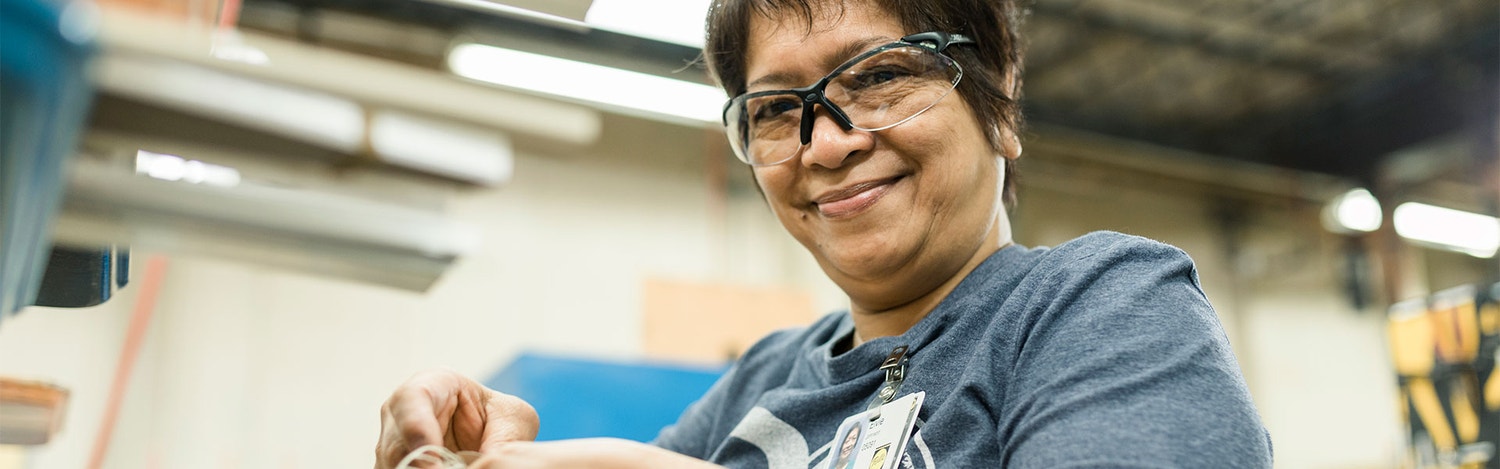 a woman who works in the factory is looking at the camera and smiling