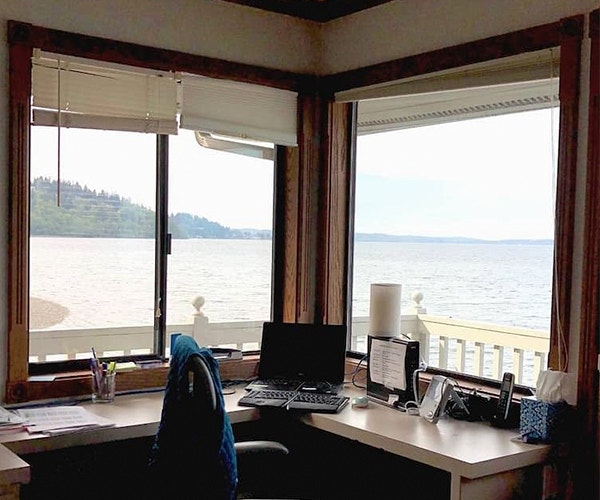 Two outdated windows form the corner of a home office overlooking the ocean