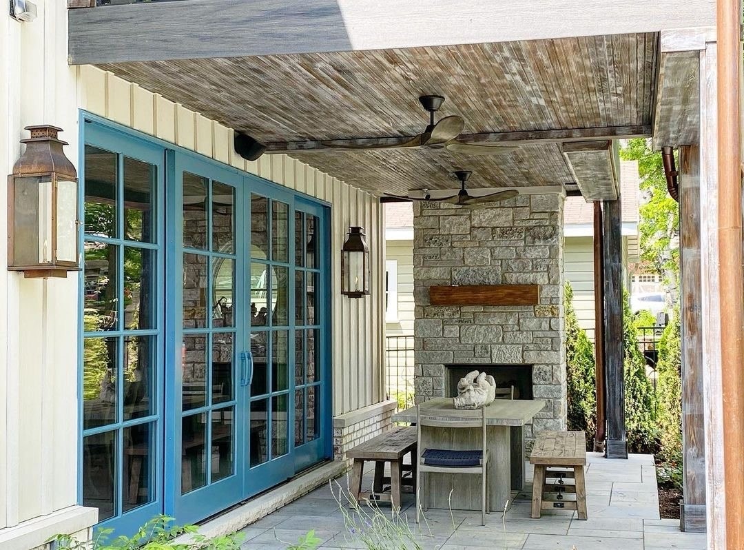 Blue sliding French doors lead out to a backyard patio with a table and fireplace.
