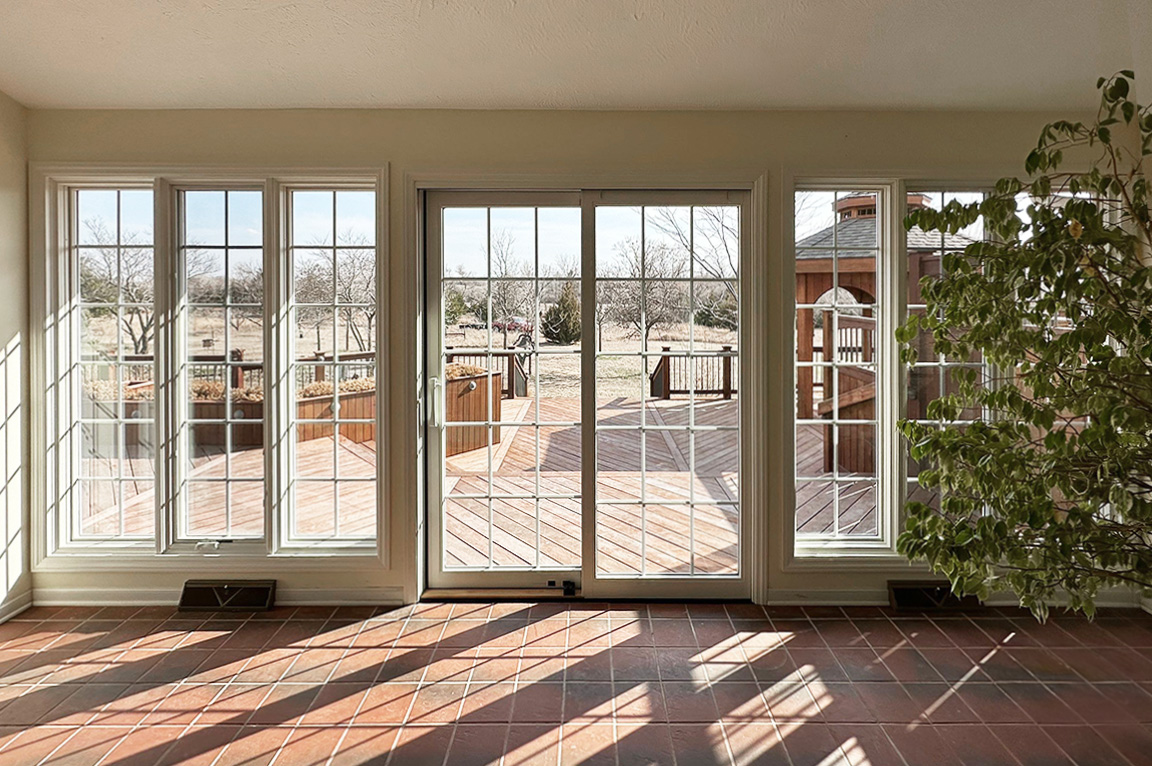 A sunroom featuring replacement windows with a view of a wooden deck and outdoor scenery.