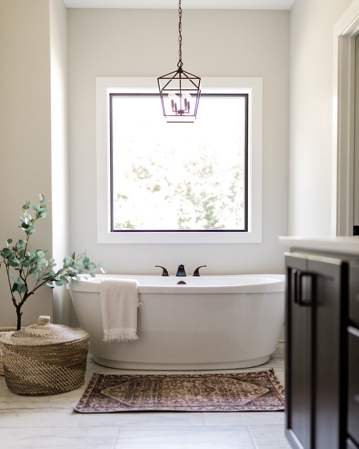 Square picture window over bathtub lets light into spa like bathroom