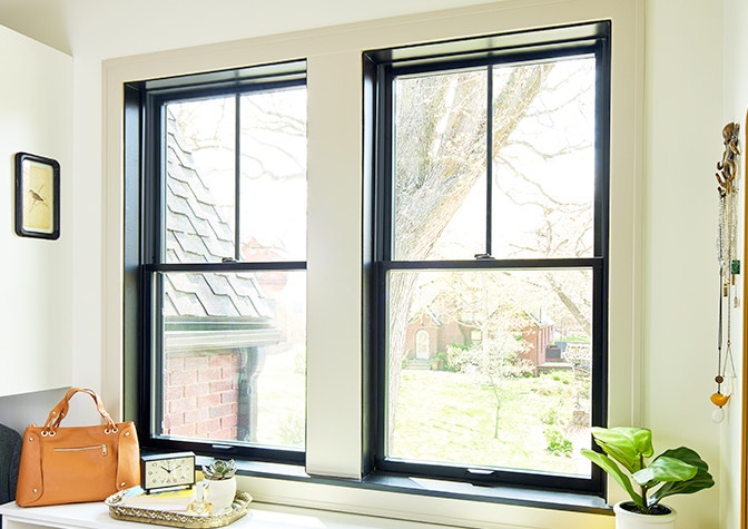 blue cabinets below marble kitchen countertops with two black wood double-hung windows.