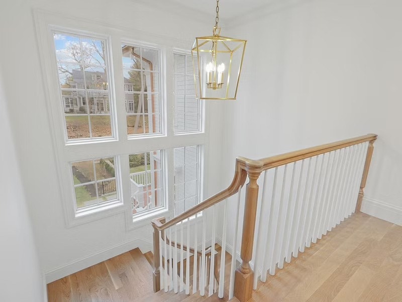 a large stairwell with a large light fixture and size white windows of varying sizes.