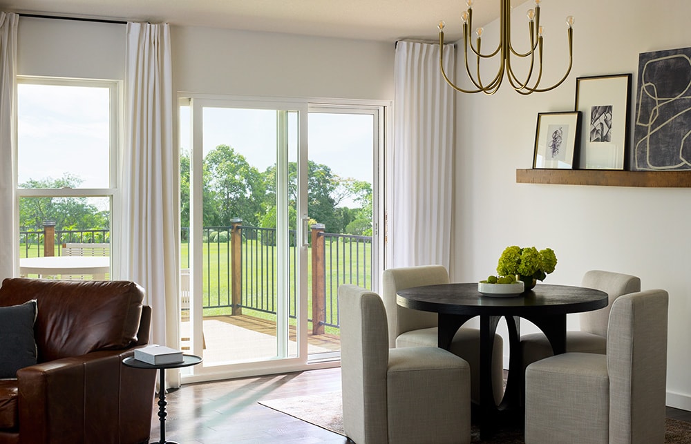 Dining room with round table and sliding glass door opening to backyard deck