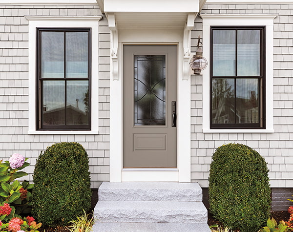 Two black double-hung windows flank a fiberglass front entry door with decorative glass
