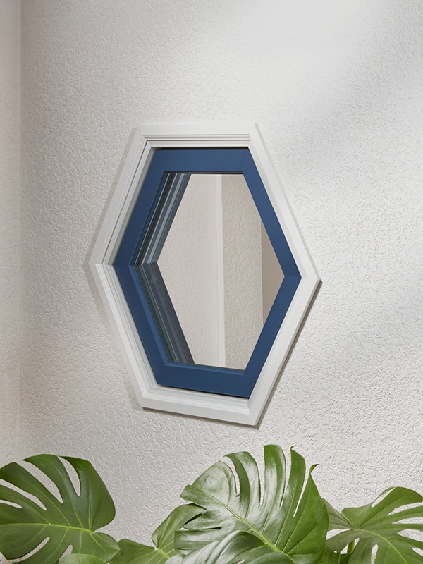 A white wall with a blue trimmed hexagon window
