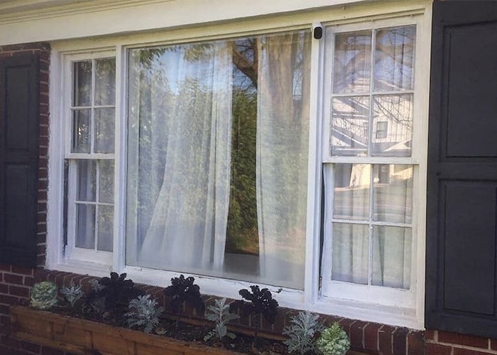 a three-window unit viewed from the exterior with fabric curtains on the interior of the home
