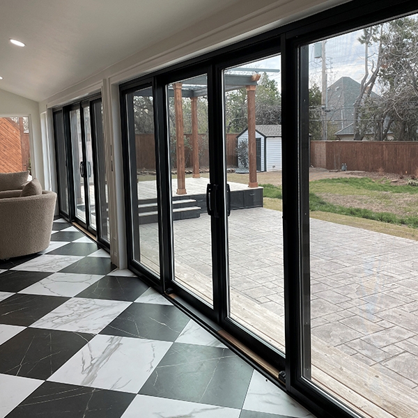 French Sliding glass doors bridge a black-and-white tiled interior floor and the stone patio exterior