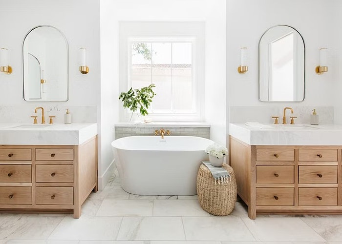 Wood vanities frame a soaker tub, which sits underneath a white wood window
