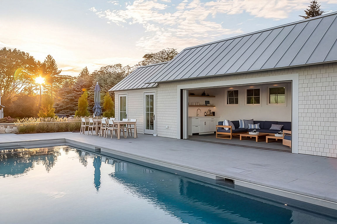 Luxury pool house with outdoor dining area and large swimming pool at sunset