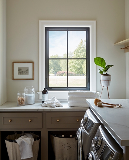 A single black window on the far side of this contemporary laundry room