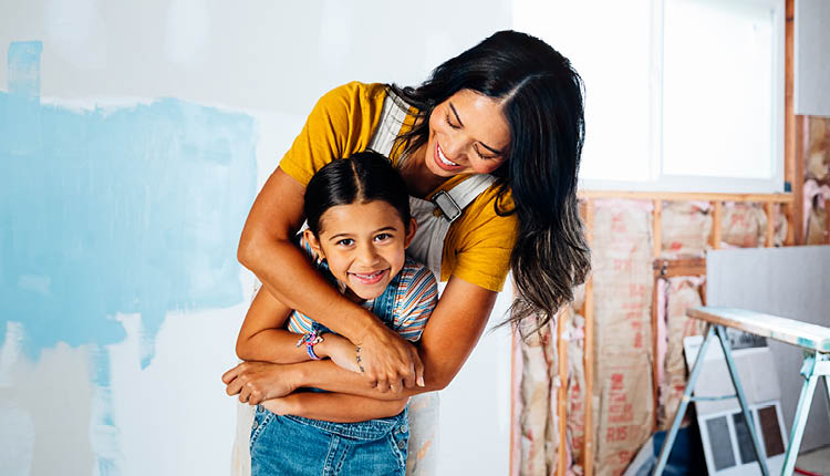Hands hammering a nail into wood.
