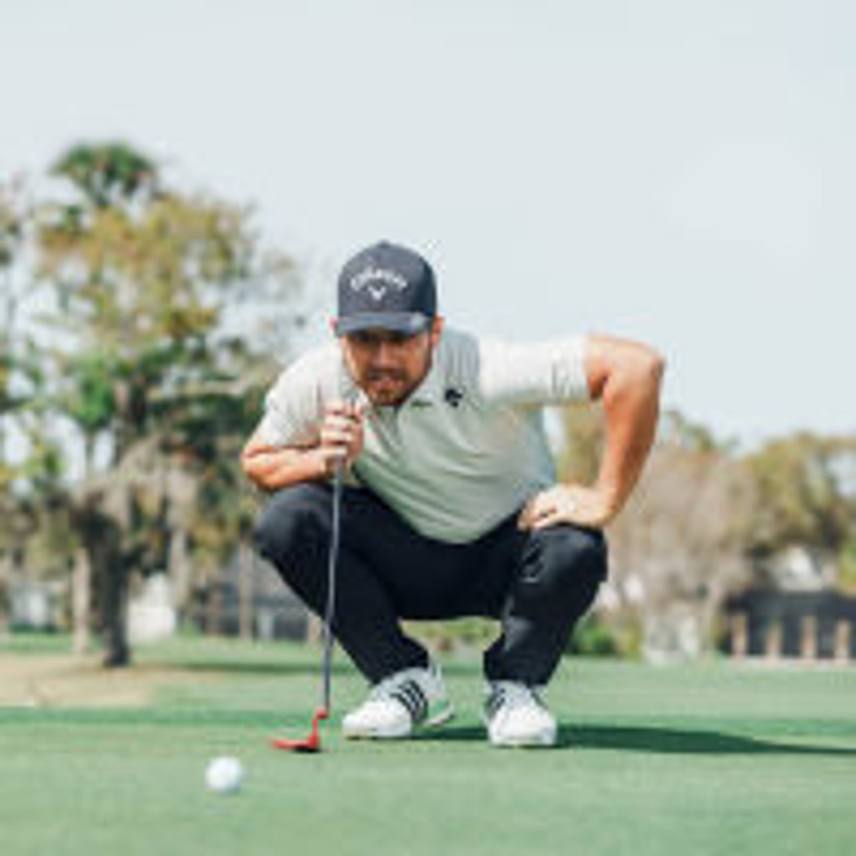 xander with his putter on green