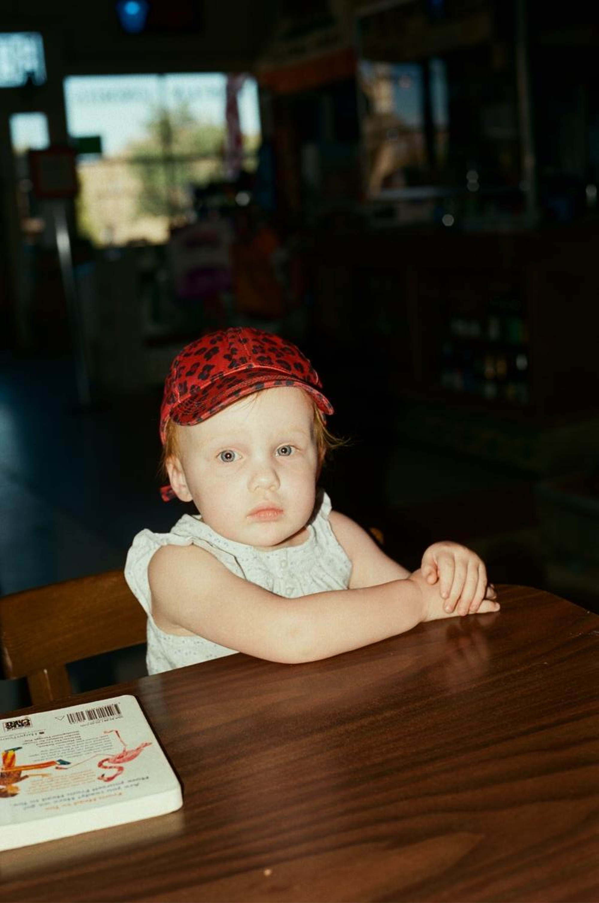 A toddler sits at a wooden table.