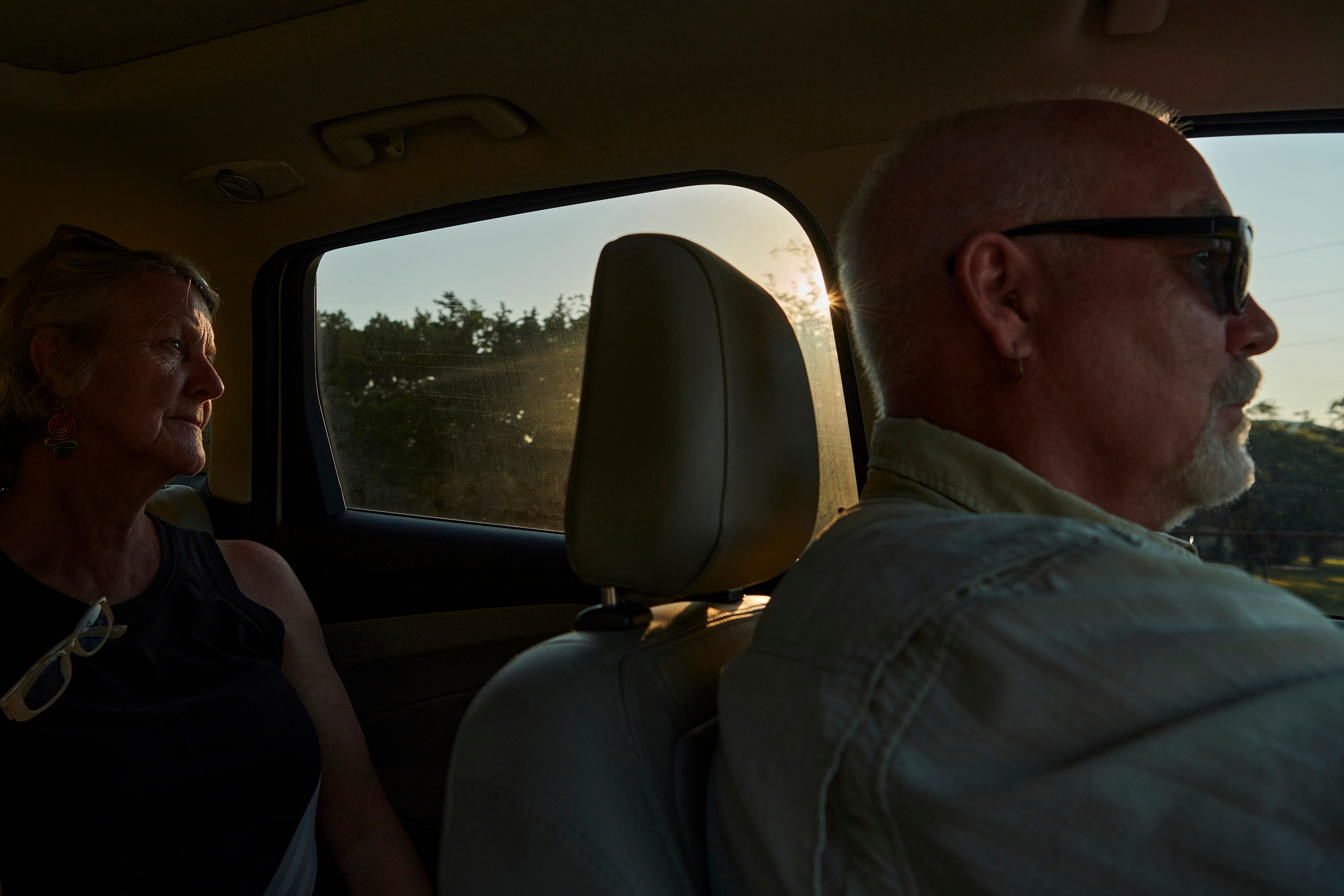 The photographer's parents Polly and Steve sitting in a car with sunlight streaming through the window.