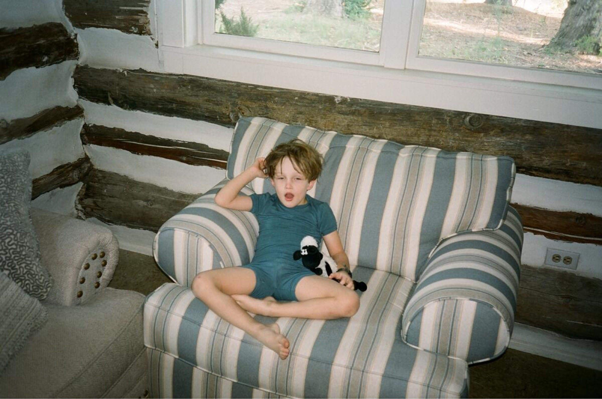 A young boy sits in a large armchair.