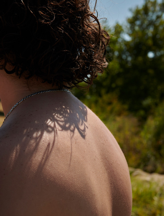 The sun creates a few shadows on the back of a young man.