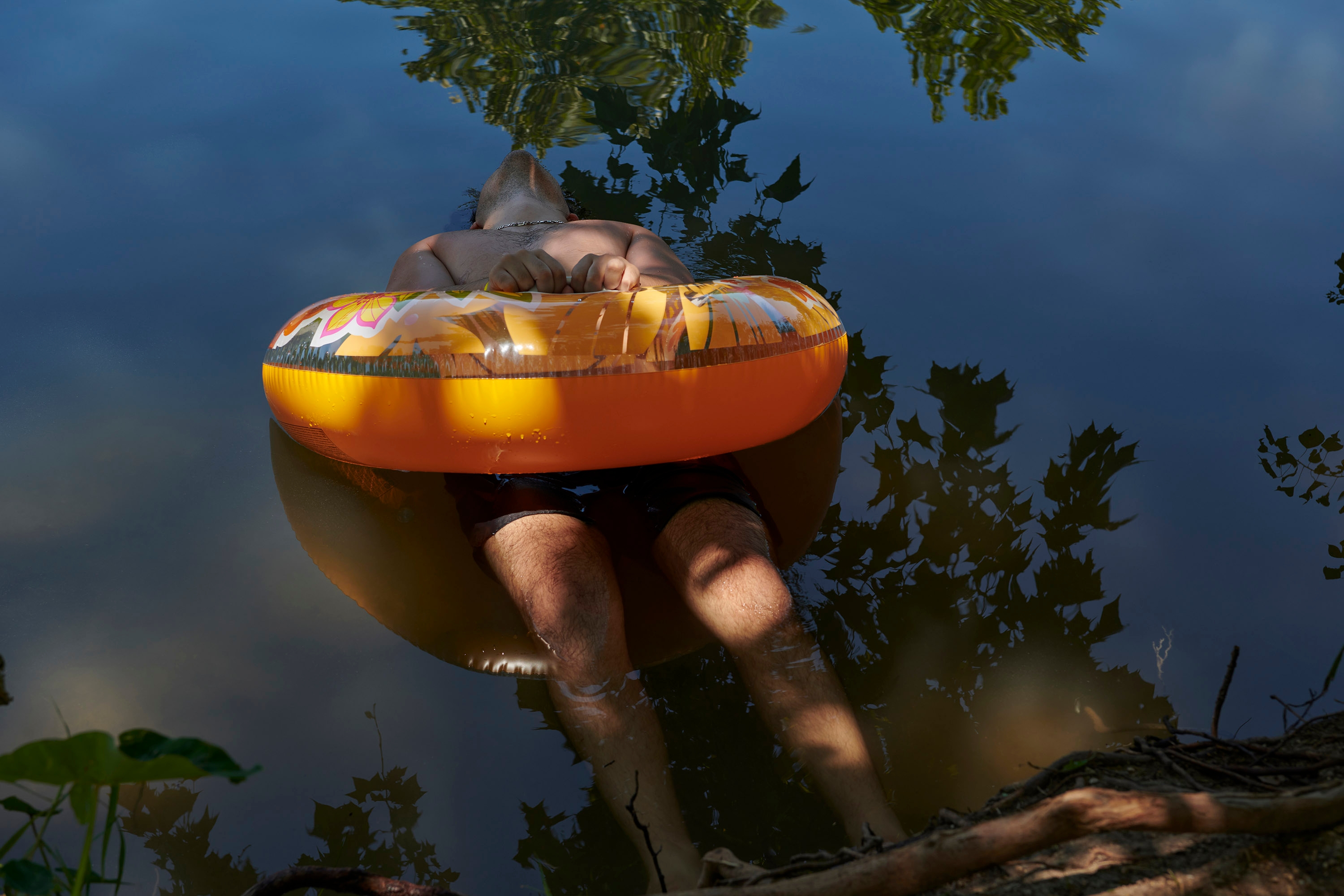 The photographer's partner Ricardo floating in the water with an orange inner tube.