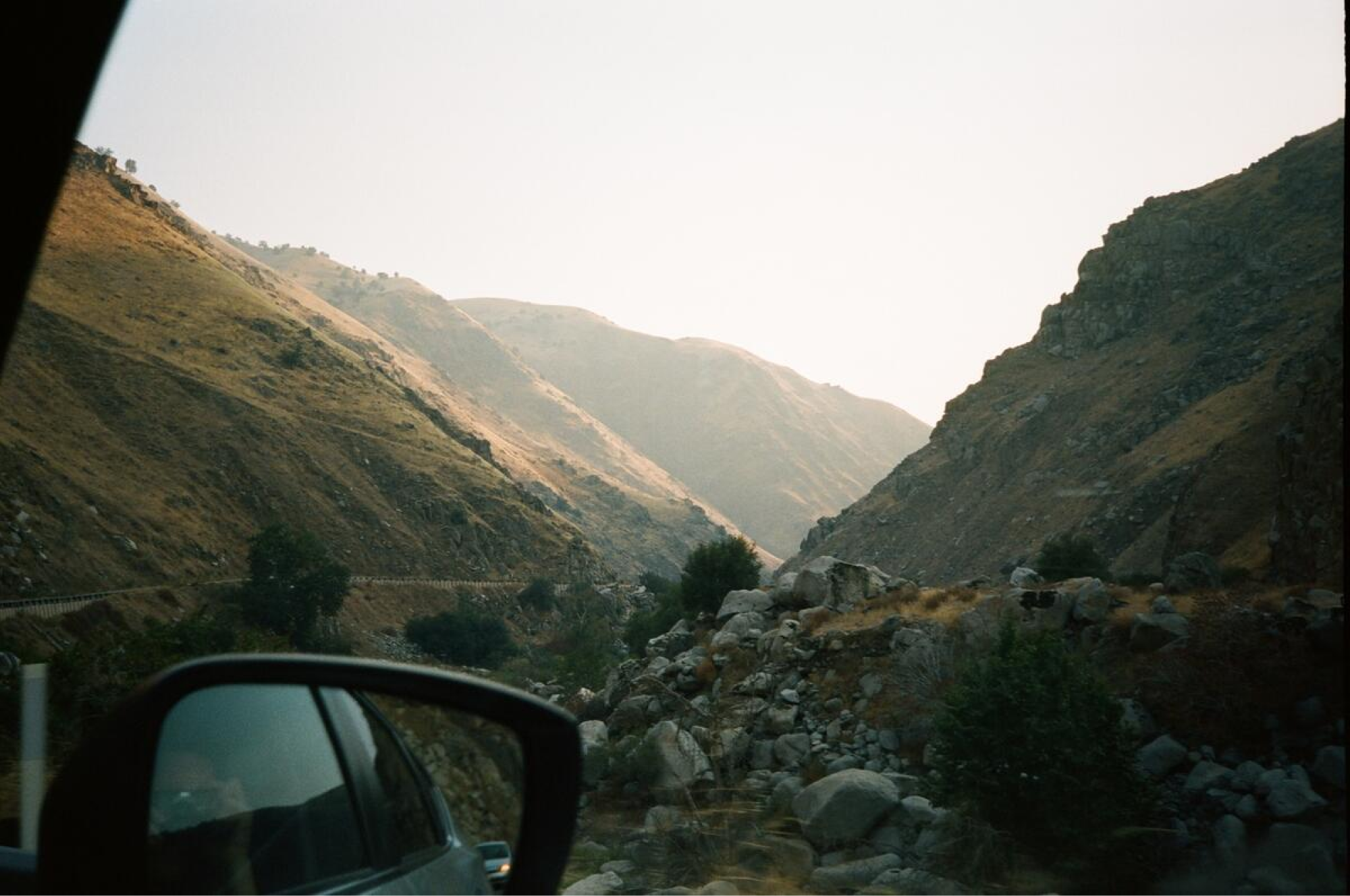 From inside of a car: past the rearview mirror, a view of a rocky canyon.