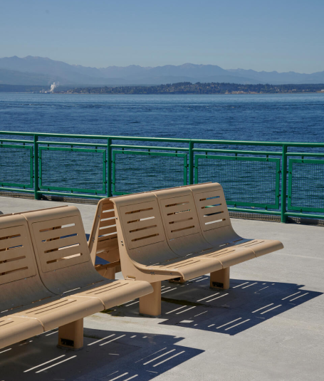 Two public benches cast a shadow on a pier overlooking the water.