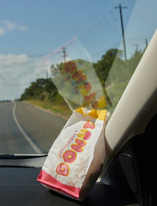 A bag of donut holes sitting on the dashboard of a car.