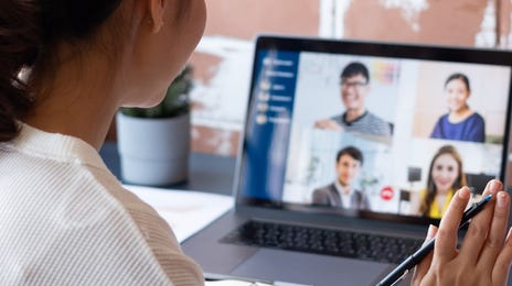 Pani macha do laptopa, na którym jest rozmowa online z innymi kursantami, biorącymi udział w kursie dla firm online.