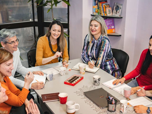 Grupa uśmiechniętych dorosłych uczy się wspólnie włoskiego