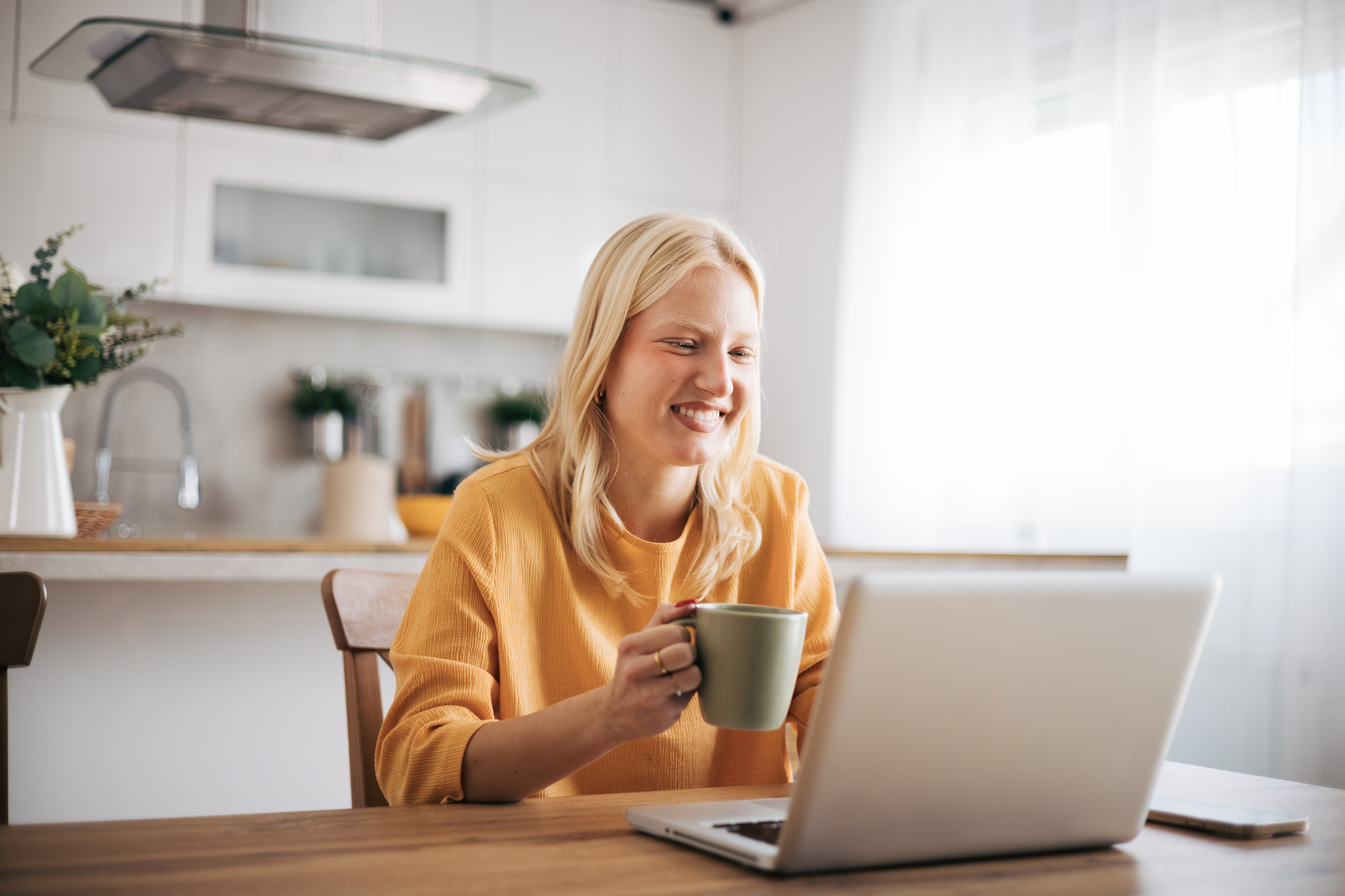 Kobieta pijąca kawę przed laptopem podczas grupowej lekcji angielskiego dla dorosłych.