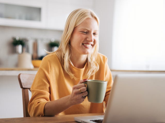 Kobieta pijąca kawę przed laptopem podczas grupowej lekcji angielskiego dla dorosłych.