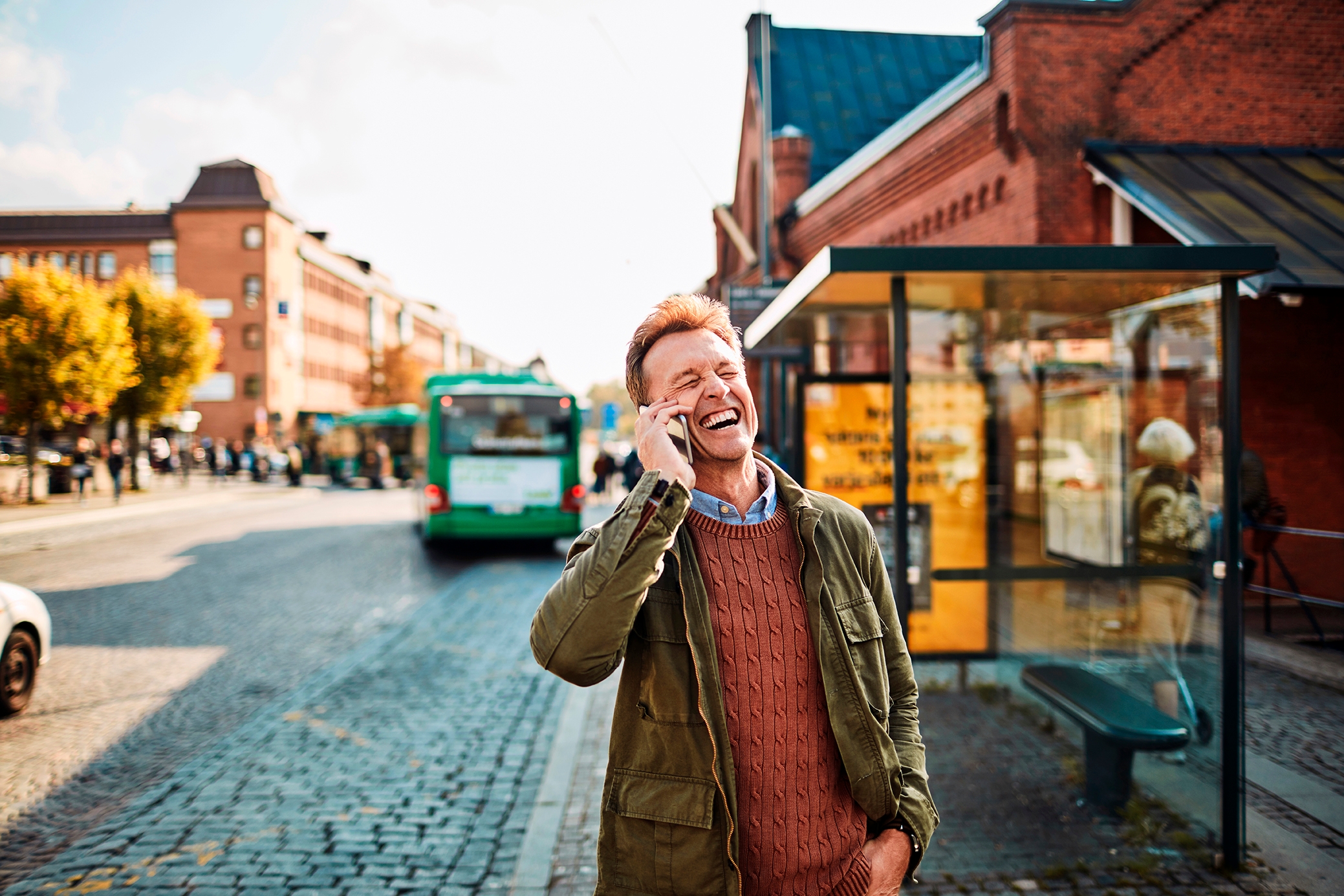 Mężczyzna w średnim wieku rozmawia przez telefon po niemiecku, idąc drogą.
