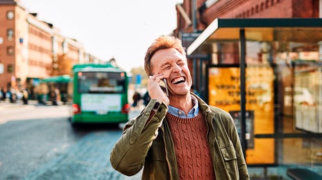 Mężczyzna w średnim wieku rozmawia przez telefon, czekając na autobus do domu po kursie języka niemieckiego z Berlitz