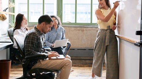 Nauczyciel niemieckiego wskazujący na tablicę, podczas stacjonarnej nauki niemieckiego w grupach.