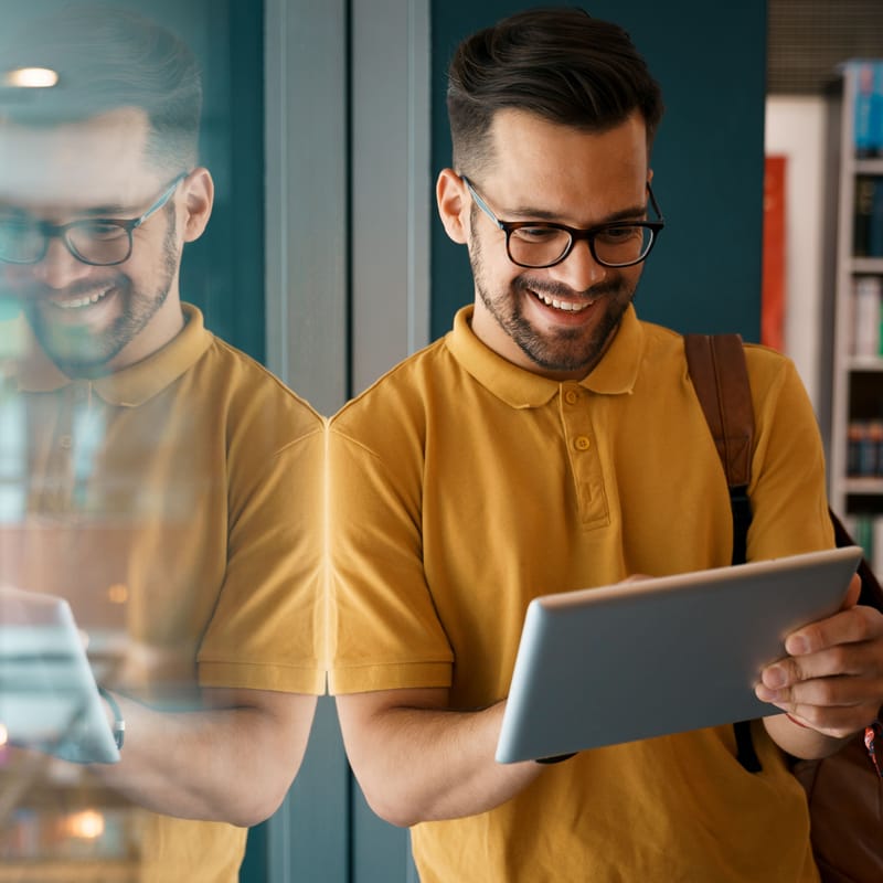 Młody mężczyzna w okularach uczy się niemieckiego online na tablecie