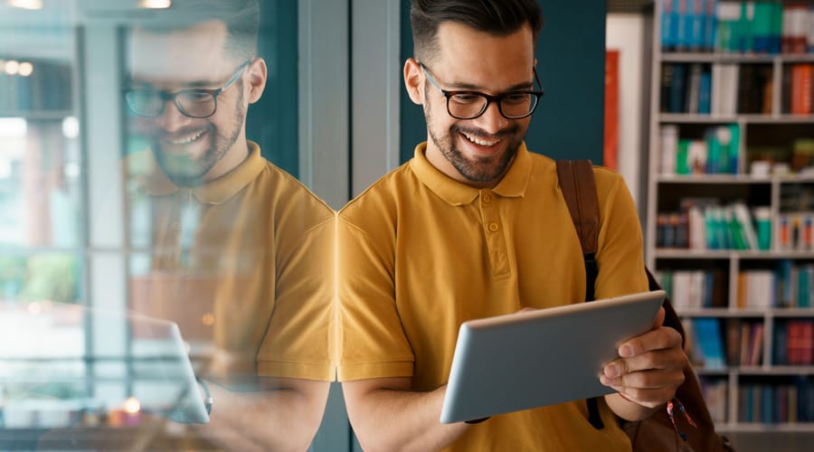 Młody mężczyzna w okularach uczy się niemieckiego online na tablecie