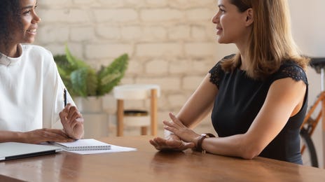 Nauczycielka tłumacząca odmianę czasownika sein po niemiecku. Kobiety siedzą przy biurku