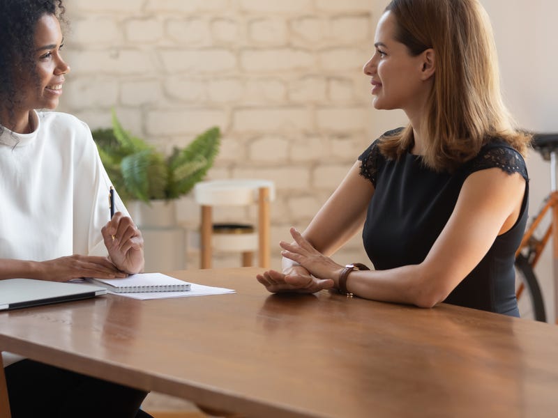 Nauczycielka tłumacząca odmianę czasownika sein po niemiecku. Kobiety siedzą przy biurku