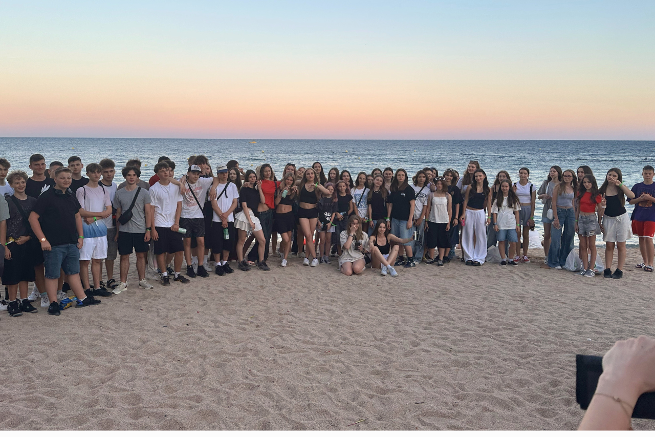 grupa młodzieży na obozie językowym w Hiszpanii, pozująca do zdjęcia, w tle widać morze