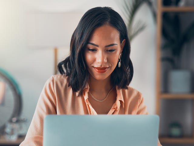 Kobieta podczas kursu francuskiego online patrzy w ekran laptopa.