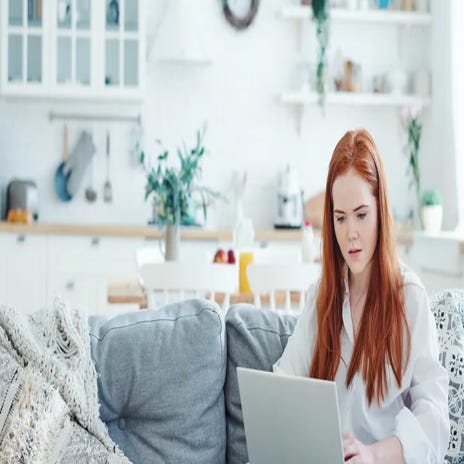 Kobieta siedząca na kanapie z laptopem na kolanach i ucząca się hiszpańskiego online