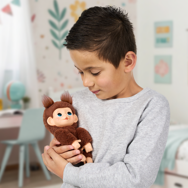 Boy cradling a brown Little Live pets mini monkey toy in his arms. 