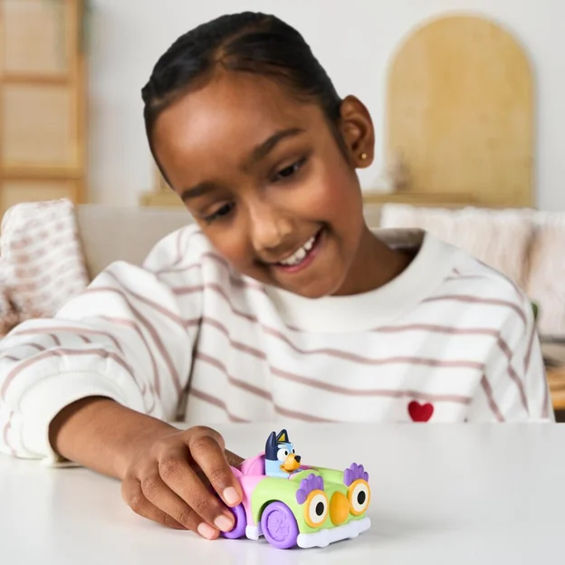 Young girl pushing a Bluey Mini Racer toy.