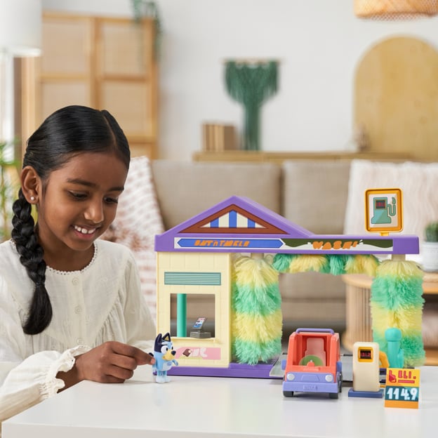 Young girl playing with a Bluey Car Wash playset. 