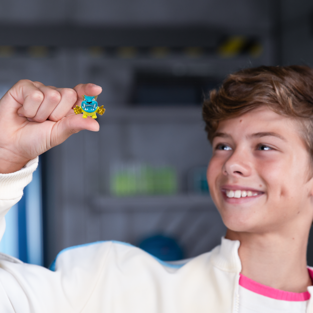 Young boy holding up swarms character in his right hand and smiling.
