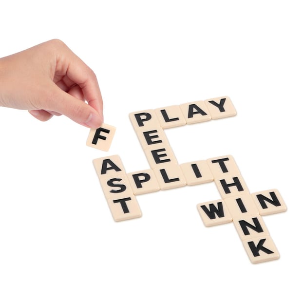 A hand holding latter tiles from the Bananagrams Big Letter game.