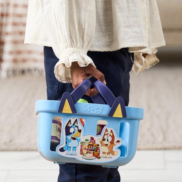 A person's hand carrying a Bluey S15 Role-Play Shopping Basket.