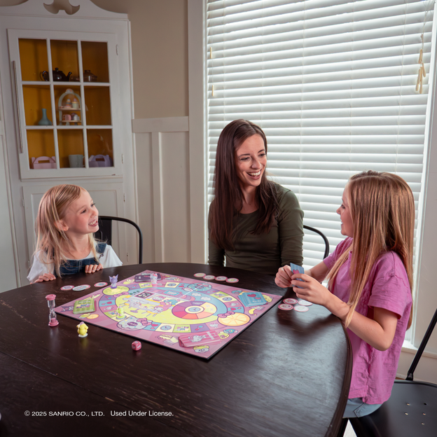 Mother and two daughters playing the Hello Kitty and Friend Snack Shop Game at the table.